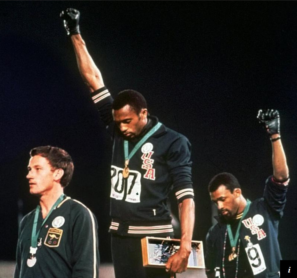 US Olympic athletes Tommie Smith and John Carlos on top of podium with one arm stretched out, with black gloved fist in protest of poverty and oppression in Black America