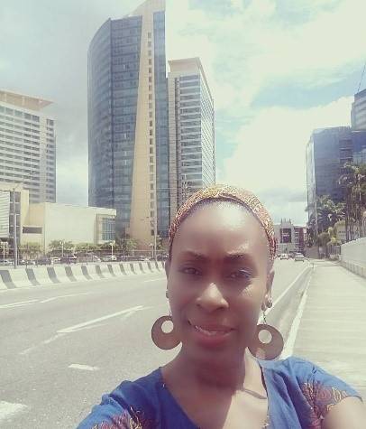 Black woman in blue top and head wrap in downtown city