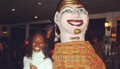 Black woman smiling and dancing with traditional Cuban character