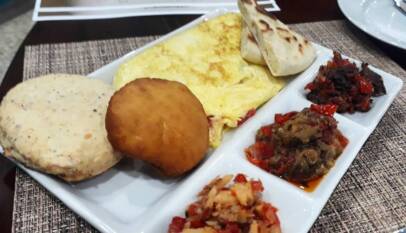 Traditional creole breakfast from Trinidad and Tobago with bake, egg, sada, tomato choka, salt fish and smoke herring