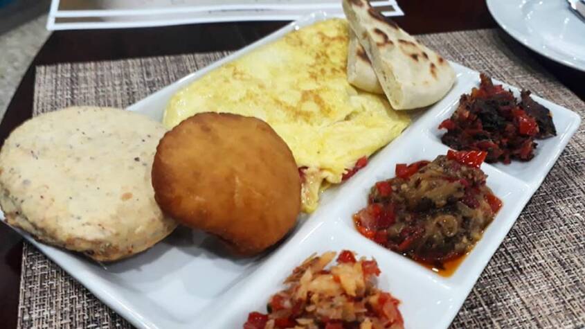 Traditional creole breakfast from Trinidad and Tobago with bake, egg, sada, tomato choka, salt fish and smoke herring