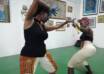 Two black women squaring off against each other in the African traditional stickfighting style, Kalinda
