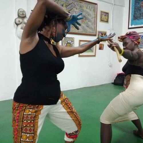 Two black women squaring off against each other in the African traditional stickfighting style, Kalinda