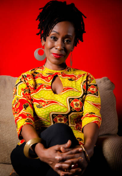 Black lady with rasta hairstyle in yellow and red colourful shirt with black long pants